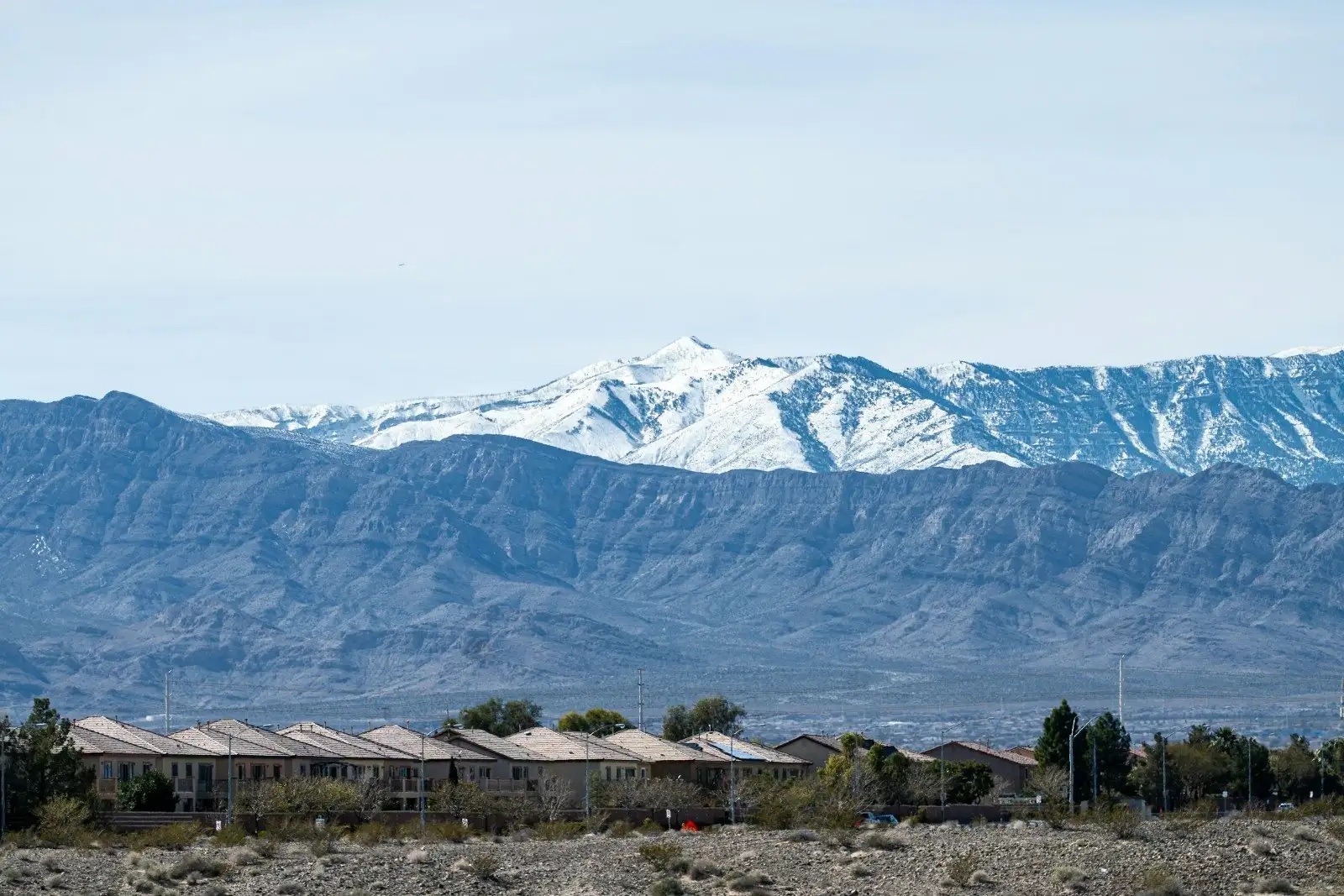 Rows of tile-roofed desert homes below a snow-capped range at the edge of the Las Vegas Valley